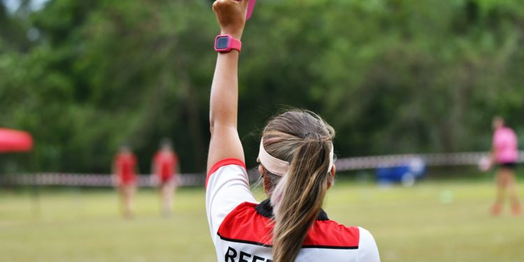 woman in white and blue shirt holding pink and white plastic tube