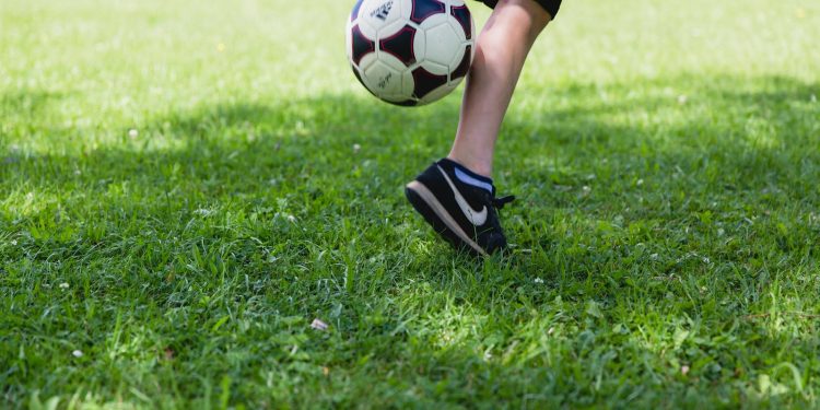 A child skillfully kicks a soccer ball on a sunny day, showcasing outdoor activity and fun.