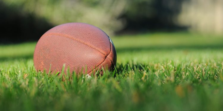 selective focus photography of brown football on grass at daytime