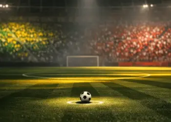 Floodlit stadium pitch at dusk with ball on penalty spot, Australian and Turkish flag colours reflected in stands.