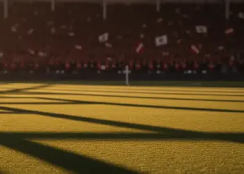 Floodlit stadium pitch with packed stands at golden hour, dramatic shadows across grass, no players visible.