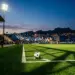 Floodlit stadium pitch at golden hour with football on centre spot and Cape Verde-coloured crowd stands visible.
