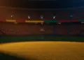 Golden-hour floodlit stadium pitch with dramatic shadows and crowd blur, Colombian yellow-red and Portuguese crimson-green lighting palette.