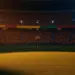 Golden-hour floodlit stadium pitch with dramatic shadows and crowd blur, Colombian yellow-red and Portuguese crimson-green lighting palette.