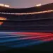 Floodlit stadium at golden hour with dramatic shadows, packed stands, and national colours in atmospheric lighting.