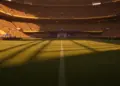 Floodlit stadium pitch at dusk with Ecuador's blue and yellow national colours in lighting, packed stands in background, geometric shadow patterns.