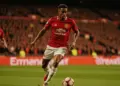 Brazilian midfielder driving forward with ball in Manchester United kit at packed Premier League stadium