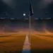 Empty floodlit stadium pitch at dusk with national flag colours in stands, shallow depth of field, dramatic lighting.