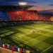 Floodlit stadium stands in multi-national flag colours with marked pitch and match ball on centre spot at dusk.