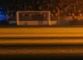 Floodlit stadium at golden-hour with packed stands and dramatic shadow patterns under warm and cool atmospheric lighting.