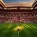 Maroon and white floodlit stadium interior with football on centre spot, evening atmosphere.