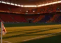 Illuminated stadium pitch at sunset with packed stands, dramatic colour-graded lighting emphasizing red and orange tones.