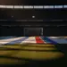 Floodlit stadium pitch at golden hour with dramatic shadows, empty field ready for match.