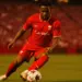 Canadian midfielder controlling ball in red jersey at packed stadium during World Cup match