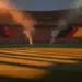 Floodlit empty stadium at dusk with Spanish and Belgian flag colours in stands, dramatic shadows, golden-hour lighting.