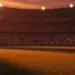 Floodlit stadium pitch at dusk with national colour stands, low-angle view, shadow patterns, no players.