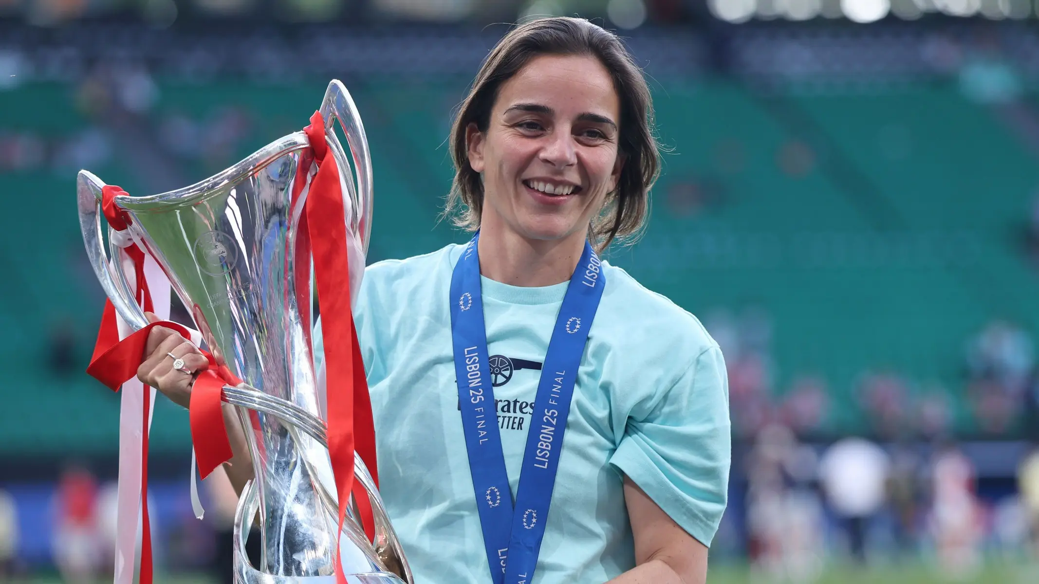 Renee Slegers smiling while holding a silver championship trophy with red ribbons.