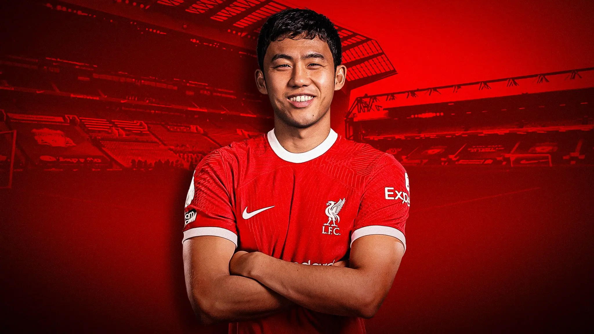 Wataru Endo wearing a red Liverpool FC home jersey with arms crossed against a red stadium background