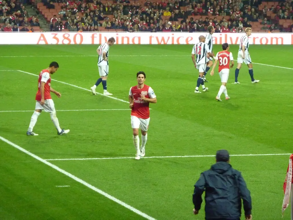 Mikel Arteta wearing an Arsenal home kit on a football pitch during a match.