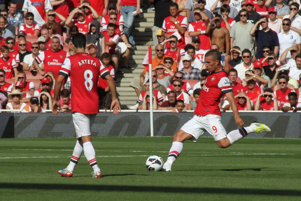 Mikel Arteta and Lukas Podolski playing for Arsenal during a match.